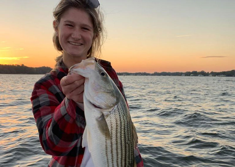 angler holds up a striped bass on the chesapeake